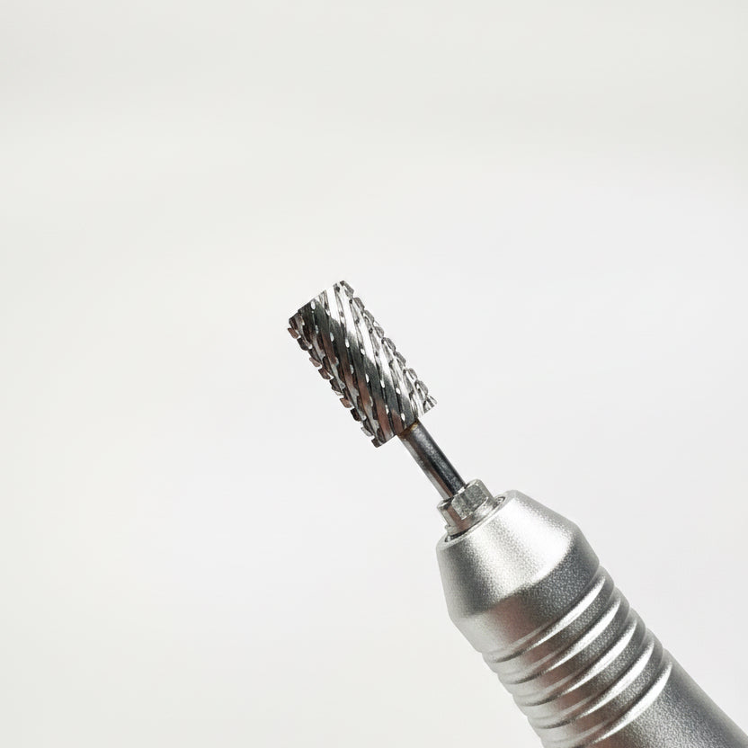 A close-up of a metallic rotary tool bit with a black bristle brush attachment, shown against a soft gray gradient background.