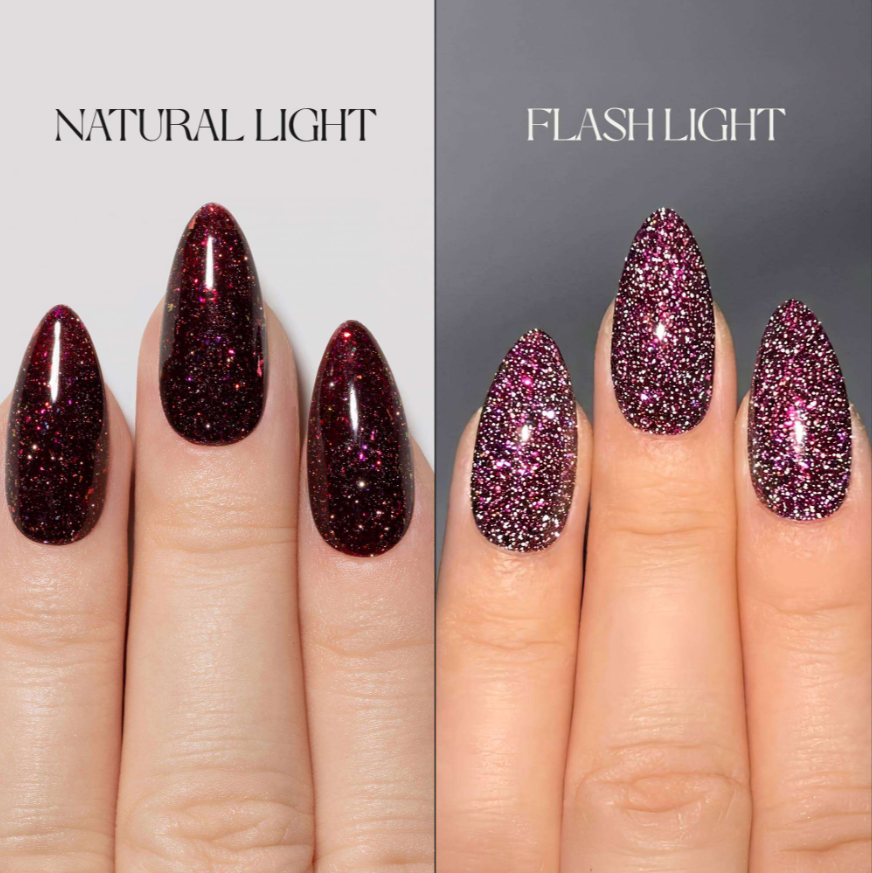 A split-screen comparison of glitter nail polish on almond-shaped nails, labeled 'NATURAL LIGHT' on the left and 'FLASH LIGHT' on the right. The left side shows dark burgundy glitter under natural light, while the right side shows a deeper plum-pink glitter under flash lighting.