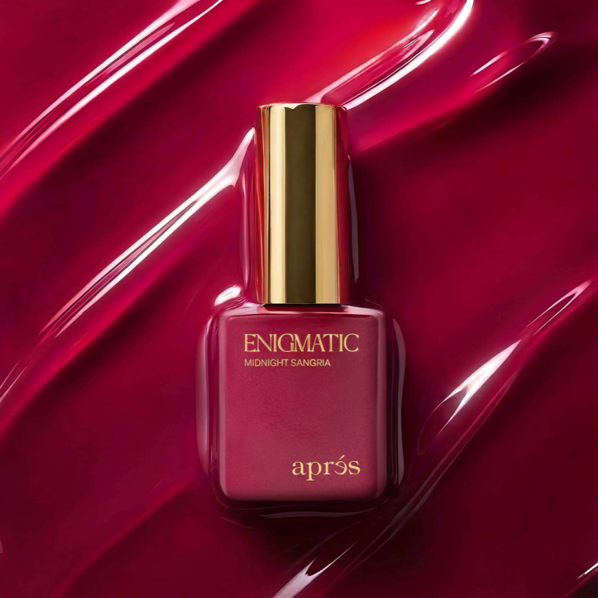Apres Enigmatic Midnight Sangria nail polish in a square glass bottle with a gold cap, set against a glossy, textured deep red background.
