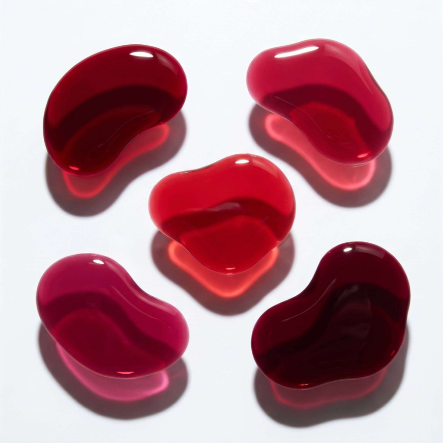 Five glossy red jelly beans arranged on a white background, each casting a soft shadow.