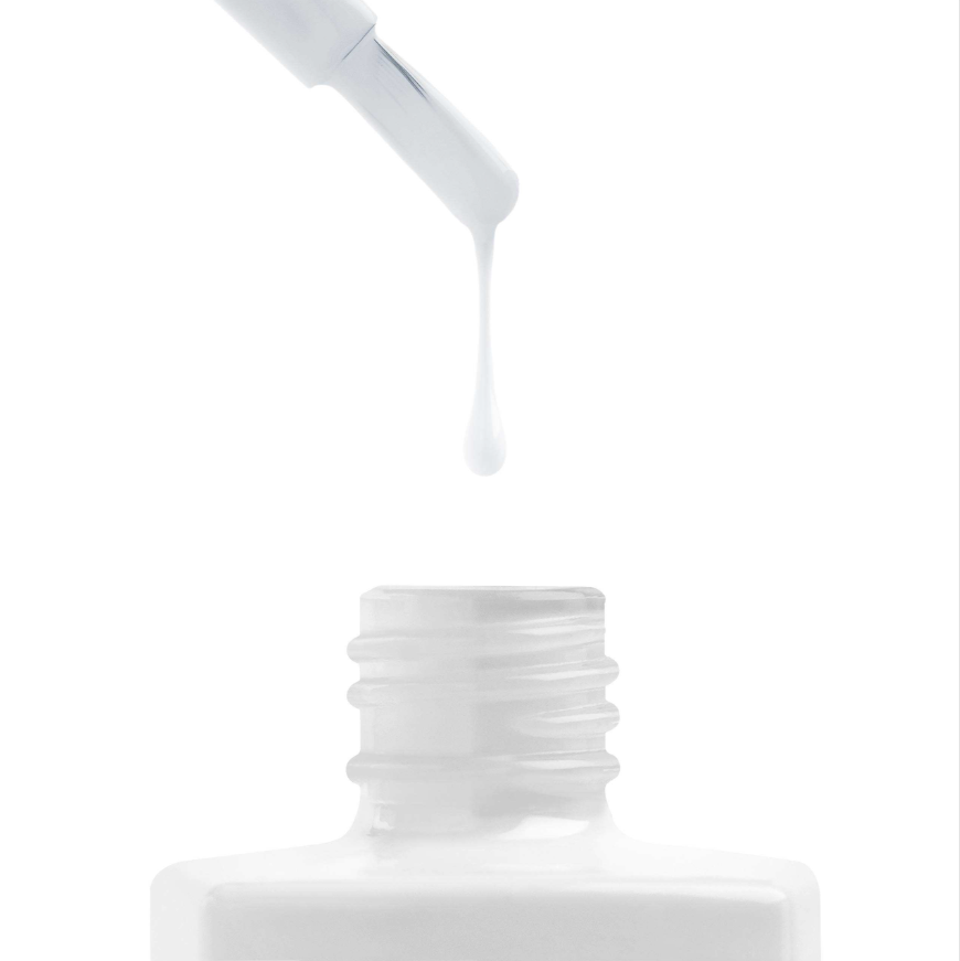 White nail polish being dripped from a brush onto a white background