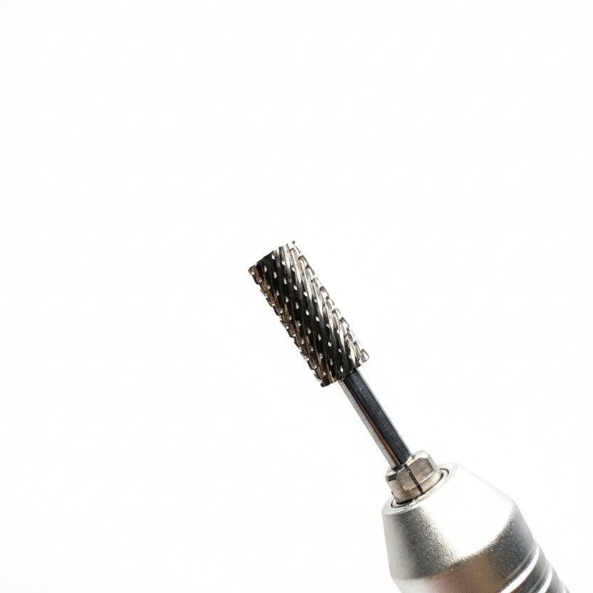 Close-up of a silver handheld rotary tool with a black textured bristle brush attachment, set against a soft gray gradient background.