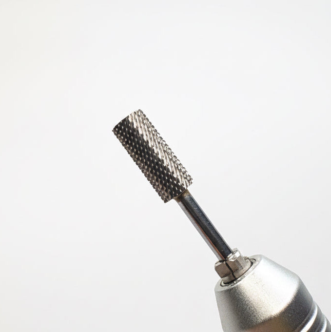 A close-up of a metallic rotary tool bit attachment with a textured, knurled diamond-like surface, shown against a soft gray gradient background.