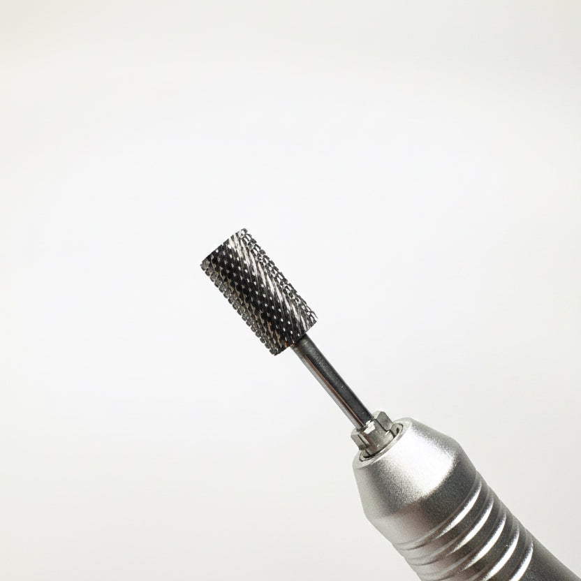 Close-up of a metallic rotary tool attachment with a small black textured brush bristle tip, shown against a soft gray gradient background.