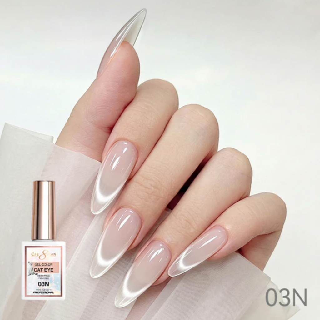 Hand with long, almond-shaped nails painted with a clear or light color, holding a bottle of nail polish labeled 'Cre8tion'.