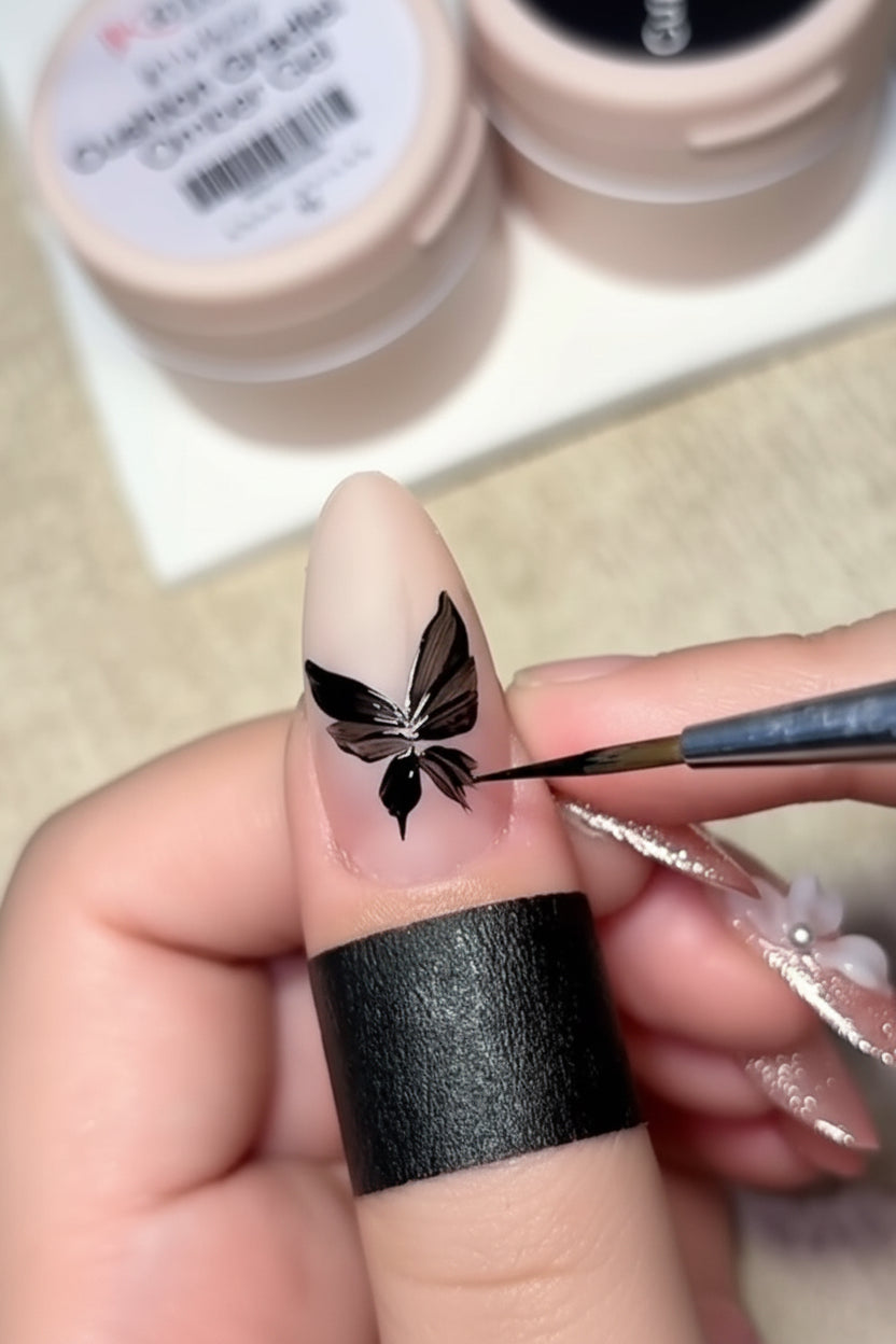 Nail art process with a butterfly design on a painted nail, using a brush.