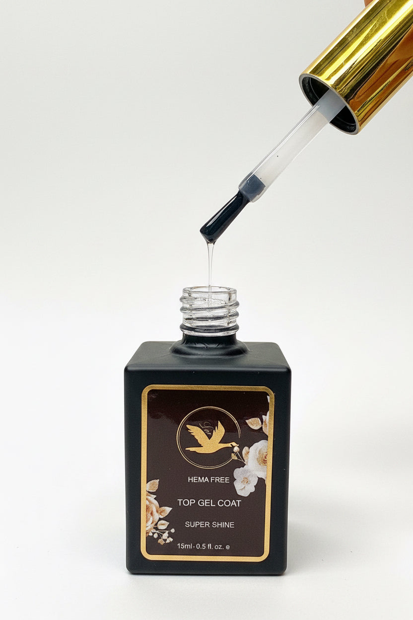 A bottle of HEMA-free top gel coat nail polish with a gold cap, shown with the applicator dropper tilted above the open bottle, dispensing a clear liquid on a white background.