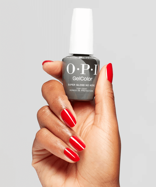 Hand holding a bottle of OPI GelColor nail polish with red nails on a gray background