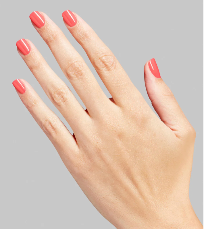 Hand with pink nail polish on a gray background