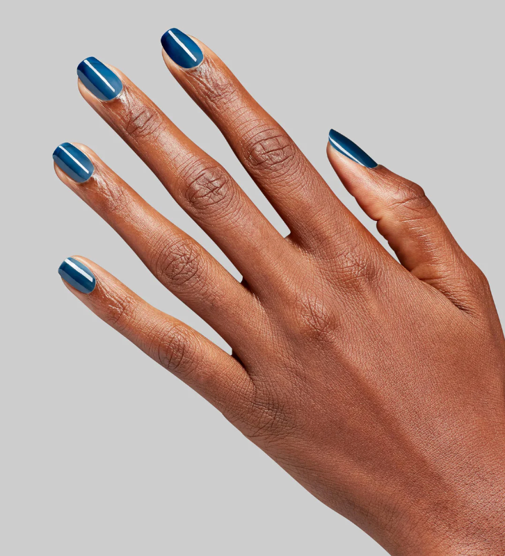 Hand with blue nail polish on a gray background