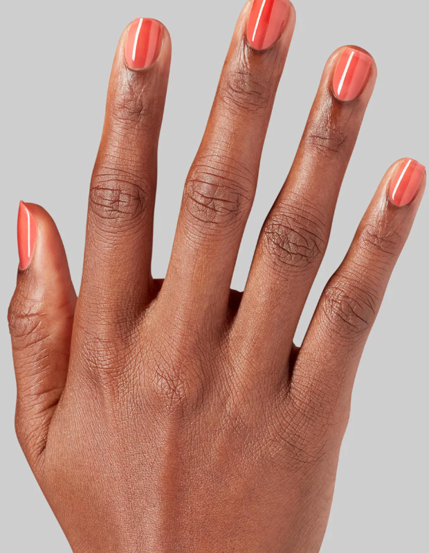 Hand with pink nail polish on a gray background