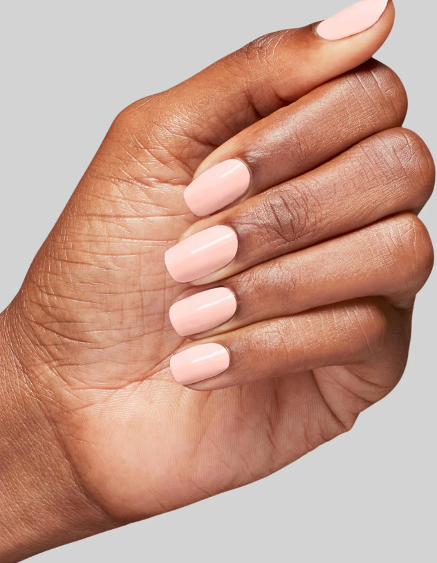 Hand with light pink nail polish on a neutral background