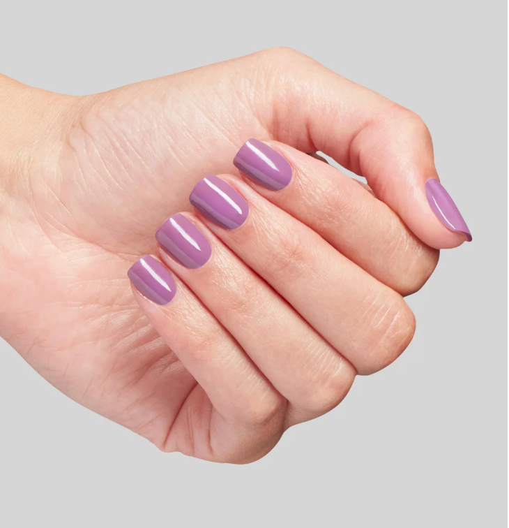 Hand with purple nail polish on a gray background