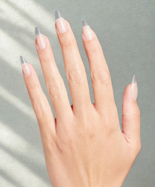 Hand with nails painted in a light color and gray tips on a neutral background
