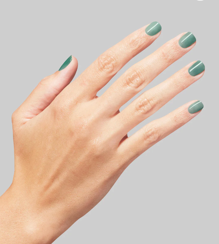 Hand with green nail polish on a gray background