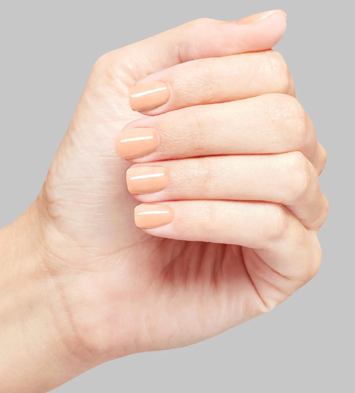 Close-up of a hand with neatly manicured nails on a gray background