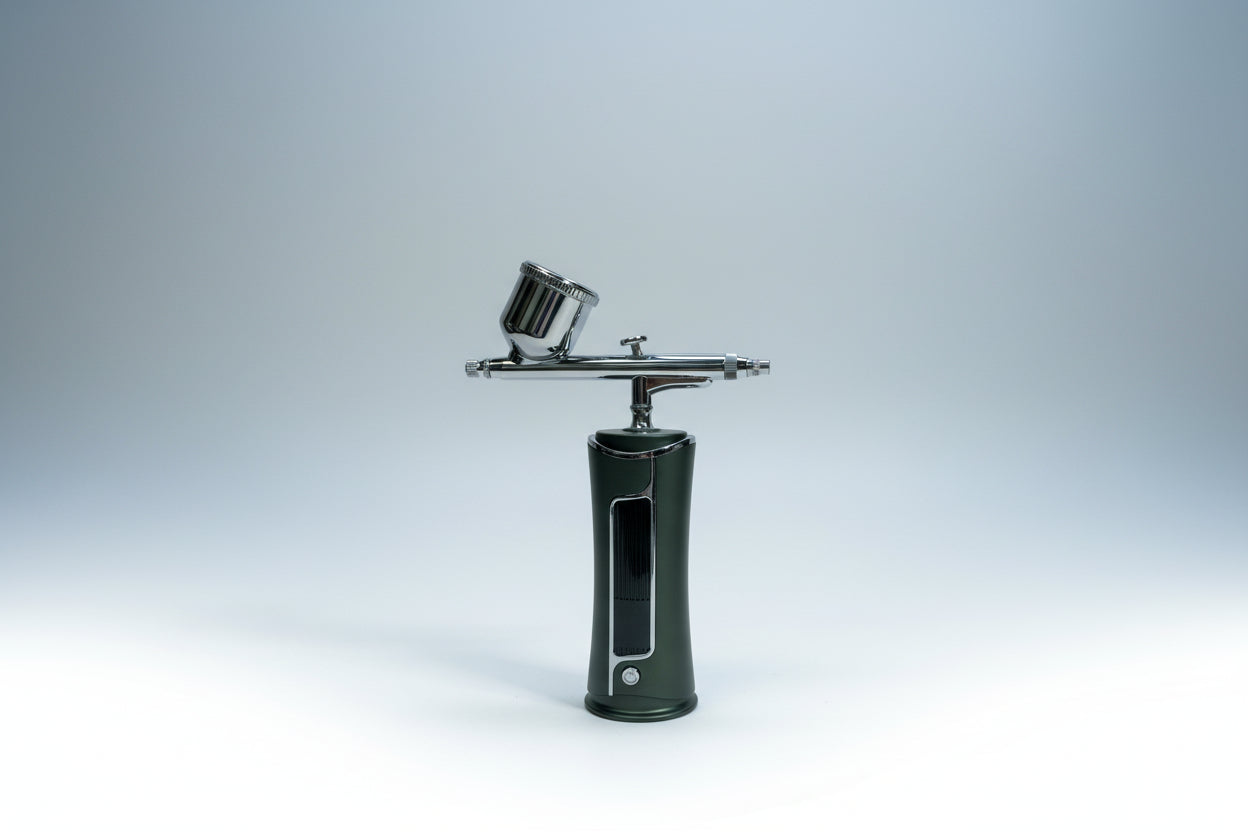 Airbrush with a clear plastic cup attachment on a white background