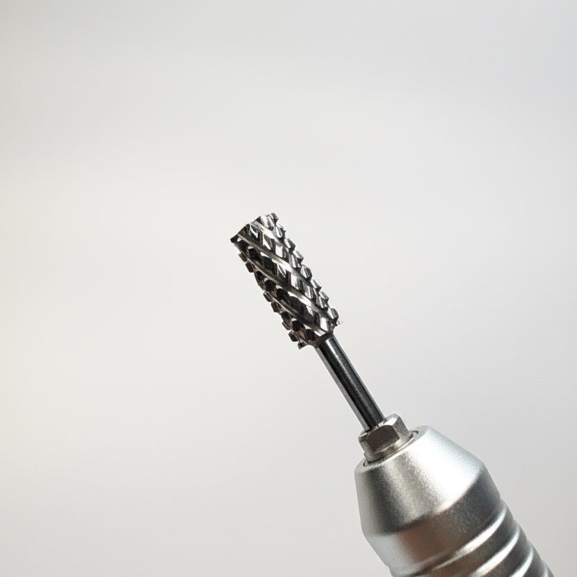 A close-up of a silver rotary tool bit with a textured, multi-toothed cutting head, shown against a neutral gray background.