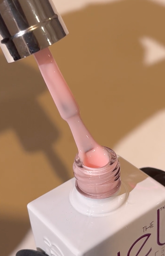 Nail polish being applied with a brush, close-up on a beige background