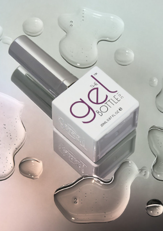 Gel bottle with applicator on a reflective surface with gel droplets